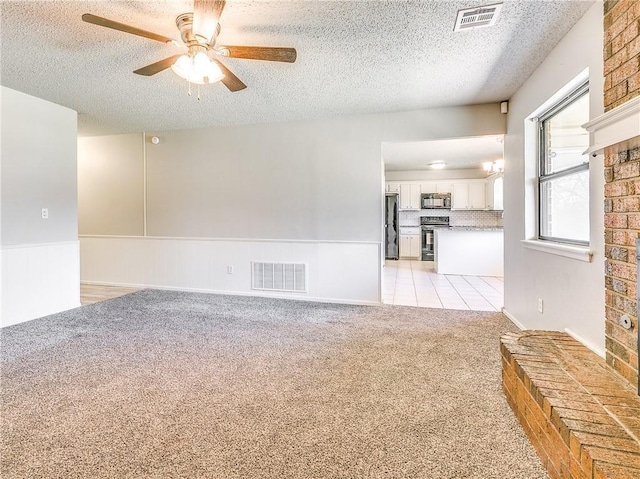 empty room with light carpet, a wainscoted wall, and visible vents