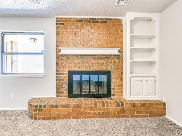 room details featuring built in shelves, visible vents, a brick fireplace, carpet flooring, and a textured ceiling