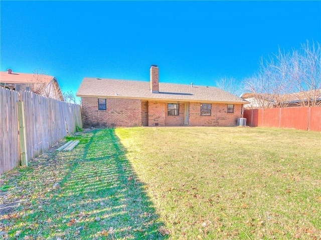 rear view of property with central AC, brick siding, a lawn, and a fenced backyard