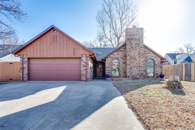 view of front facade with brick siding, a chimney, fence, a garage, and driveway