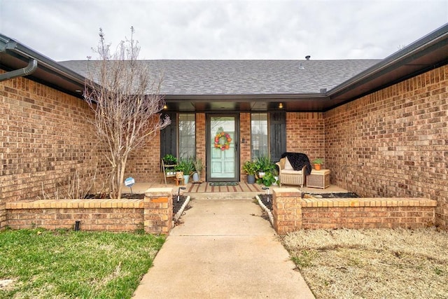 property entrance featuring brick siding and roof with shingles