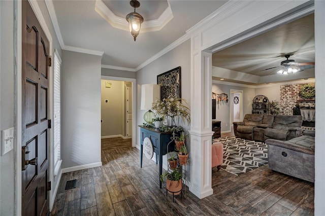 foyer featuring baseboards, visible vents, dark wood-style flooring, ornamental molding, and a raised ceiling