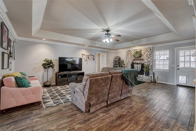 living room featuring a tray ceiling, dark wood-type flooring, and ornamental molding