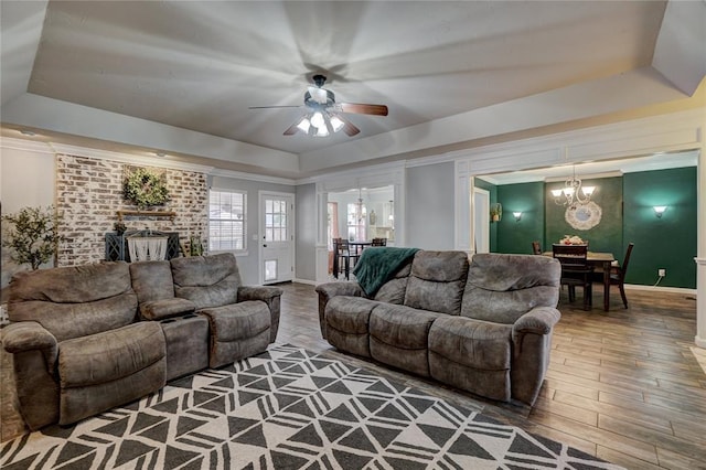 living room with a tray ceiling, wood finished floors, baseboards, and ornamental molding