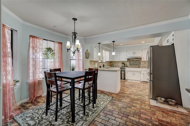 dining space with an inviting chandelier, baseboards, brick floor, and ornamental molding