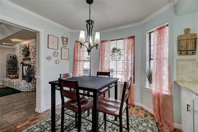 dining space featuring an inviting chandelier, baseboards, brick floor, and ornamental molding