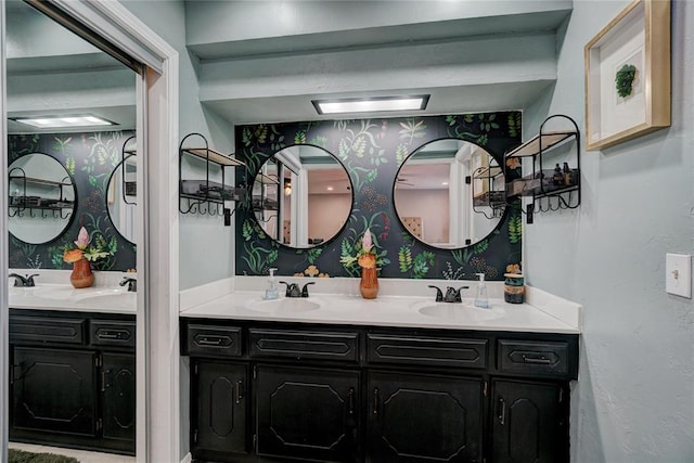 full bath with a sink, double vanity, and wallpapered walls