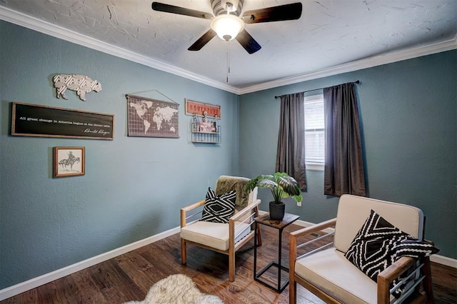 living area featuring ceiling fan, baseboards, wood finished floors, ornamental molding, and a textured wall