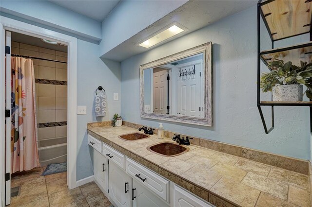 full bathroom featuring double vanity, shower / bath combo with shower curtain, baseboards, and a sink