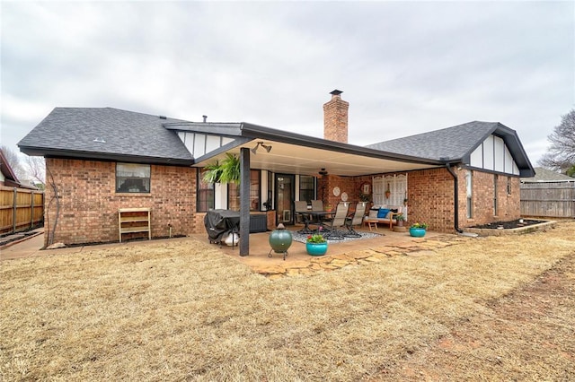 back of property with fence, roof with shingles, a chimney, a patio area, and brick siding