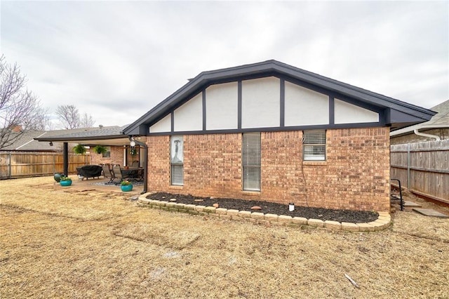 back of house featuring a patio, brick siding, and fence