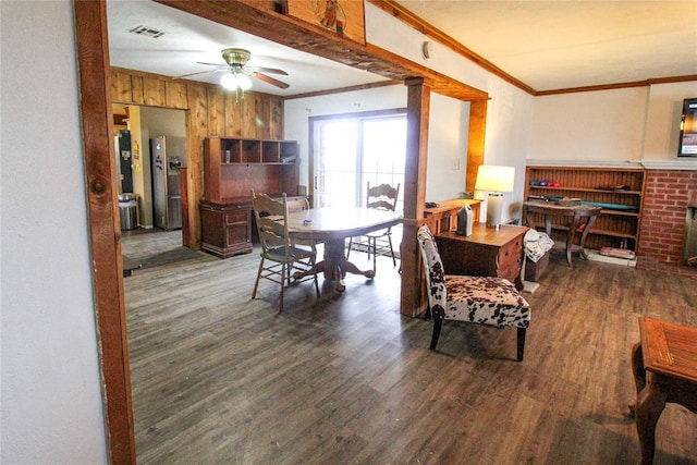 dining room featuring visible vents, ornamental molding, a fireplace, wood finished floors, and a ceiling fan