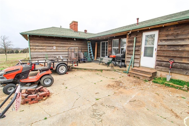 rear view of house with entry steps, a patio, and a chimney