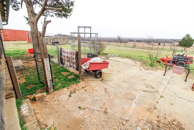 view of patio / terrace with an outbuilding, a rural view, and fence