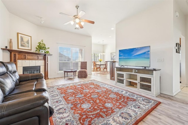 living room featuring baseboards, ceiling fan, a tiled fireplace, recessed lighting, and wood finished floors