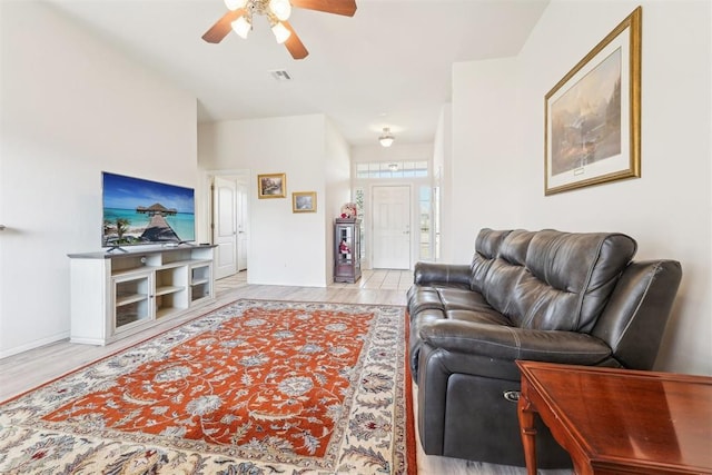 living area with baseboards, a ceiling fan, and light wood finished floors