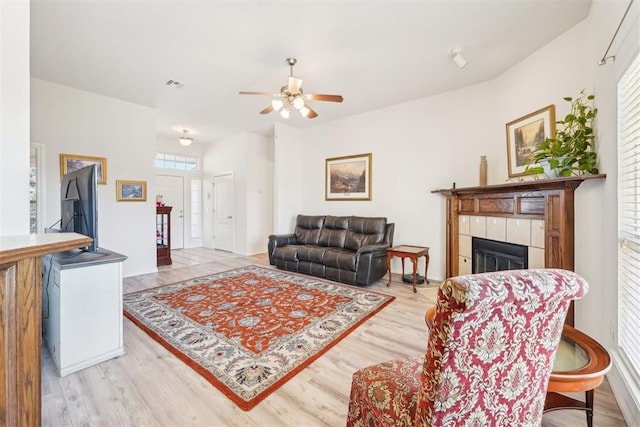 living area featuring visible vents, a ceiling fan, wood finished floors, and a fireplace