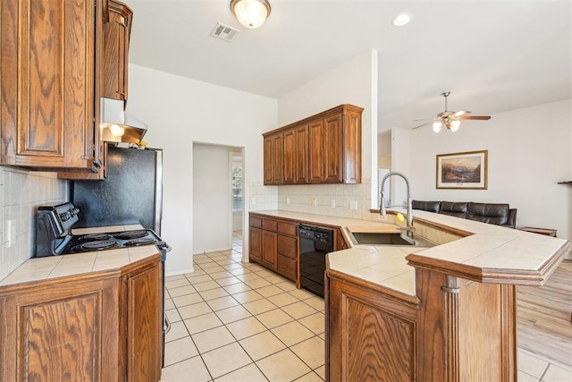 kitchen featuring black appliances, tile counters, a peninsula, and a sink