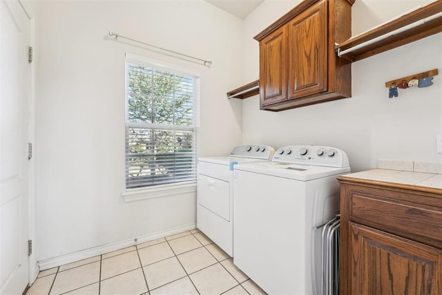 washroom with washer and dryer, baseboards, cabinet space, and light tile patterned floors