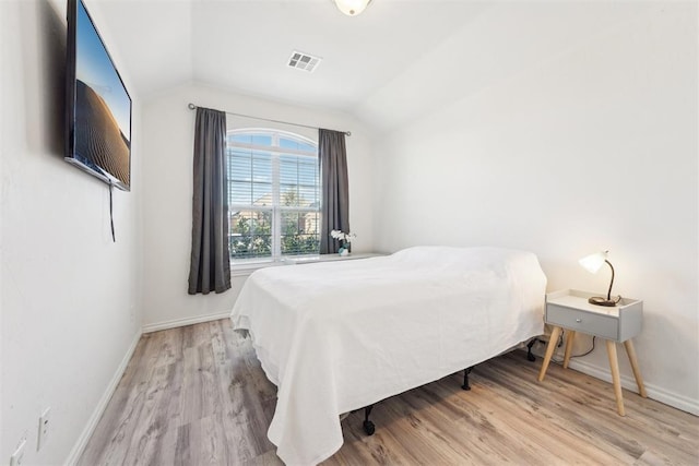 bedroom featuring lofted ceiling, wood finished floors, visible vents, and baseboards