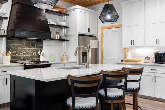 kitchen featuring premium range hood, stove, stainless steel fridge with ice dispenser, decorative backsplash, and open shelves