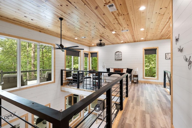 interior space with a wealth of natural light, light wood-type flooring, wood ceiling, and visible vents