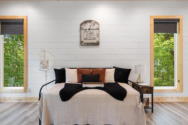 bedroom with wood walls, baseboards, and wood finished floors