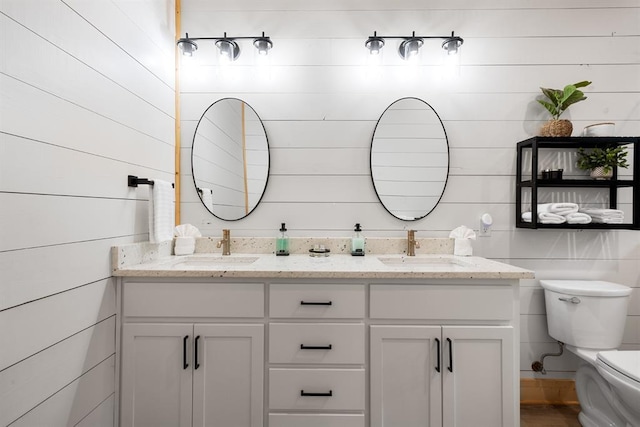 bathroom featuring double vanity, a sink, and toilet