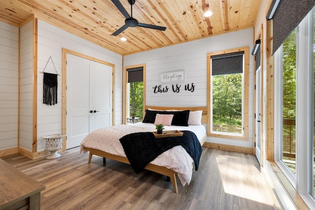 bedroom with wooden ceiling, a closet, wooden walls, and wood finished floors