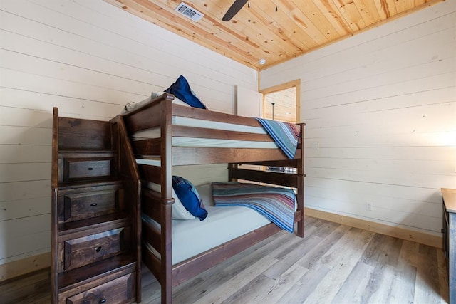 bedroom featuring wood walls, wood finished floors, wood ceiling, visible vents, and baseboards