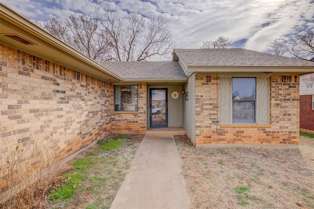 entrance to property with brick siding and roof with shingles