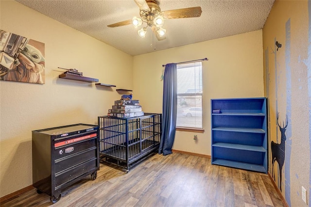 miscellaneous room with ceiling fan, wood finished floors, baseboards, and a textured ceiling