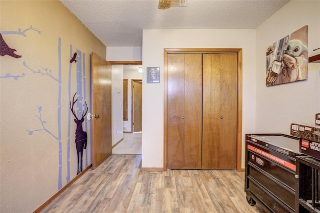 interior space featuring a closet, a textured ceiling, visible vents, and light wood finished floors