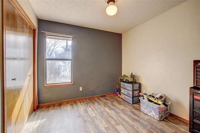 interior space with wood finished floors, baseboards, and a textured ceiling