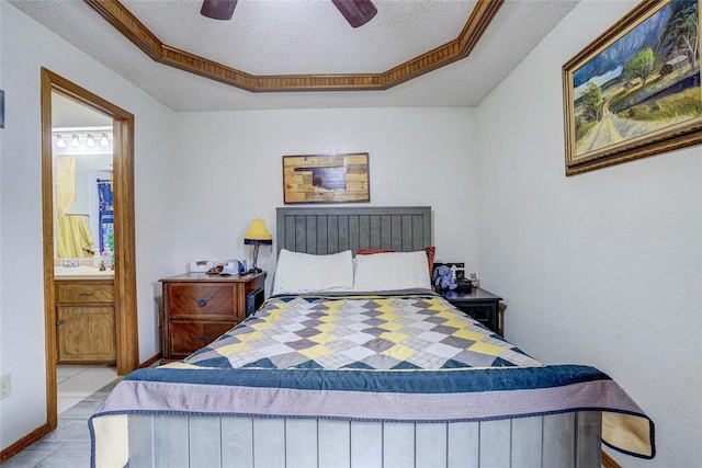 tiled bedroom featuring baseboards, ceiling fan, a tray ceiling, ensuite bathroom, and a textured ceiling