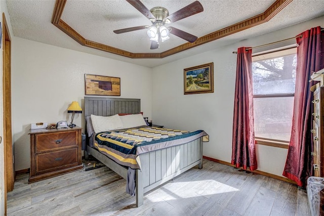 bedroom featuring a textured ceiling, a ceiling fan, baseboards, and wood finished floors