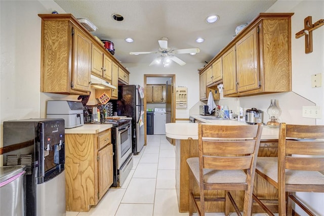 kitchen with under cabinet range hood, independent washer and dryer, appliances with stainless steel finishes, and light countertops