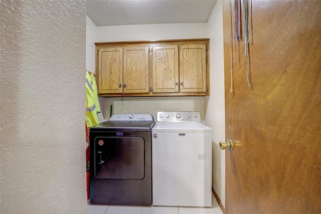 clothes washing area with cabinet space, a textured ceiling, independent washer and dryer, and a textured wall