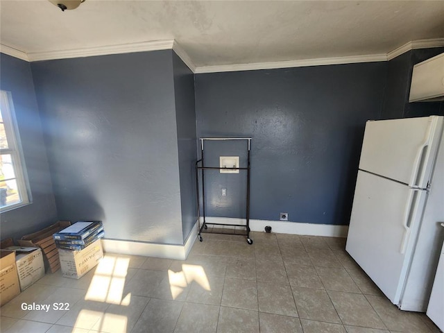 interior space with baseboards, ornamental molding, tile patterned flooring, and freestanding refrigerator