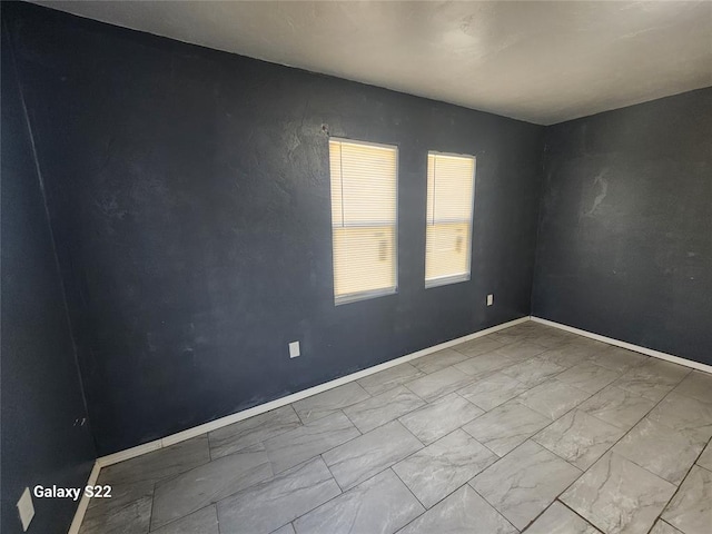 empty room featuring baseboards and marble finish floor