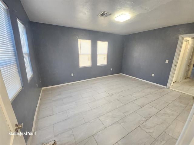 unfurnished room with visible vents, plenty of natural light, and baseboards