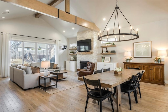 dining area with light wood finished floors, beamed ceiling, a fireplace, and high vaulted ceiling