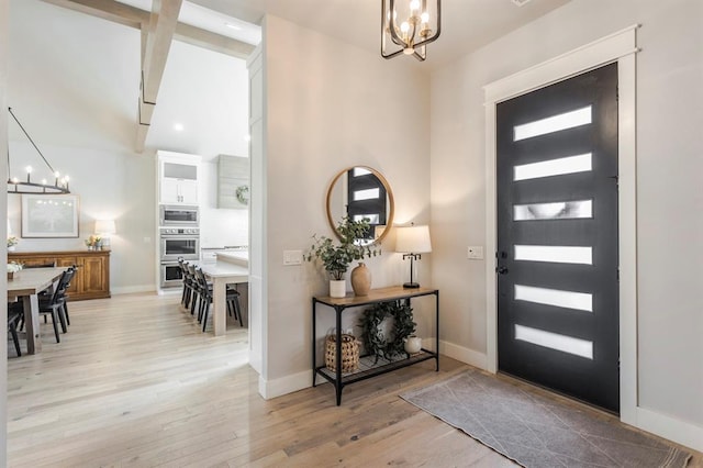 foyer entrance featuring light wood-type flooring, baseboards, and a chandelier