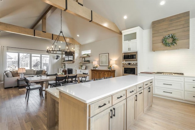 kitchen with tasteful backsplash, open floor plan, a center island, appliances with stainless steel finishes, and an inviting chandelier