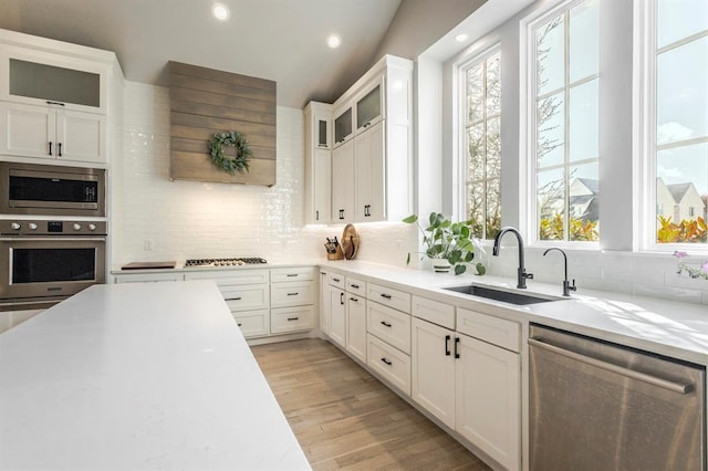 kitchen featuring a sink, stainless steel appliances, light countertops, and light wood finished floors