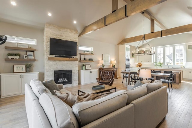 living room featuring light wood-type flooring, beamed ceiling, a notable chandelier, recessed lighting, and a fireplace