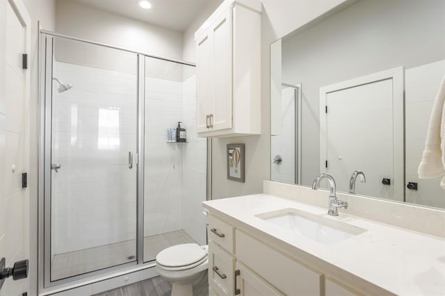 bathroom with recessed lighting, a stall shower, toilet, and vanity