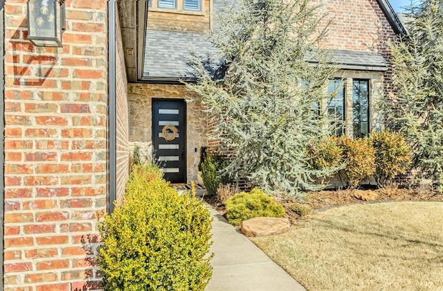 entrance to property featuring brick siding and a shingled roof