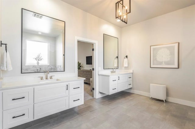 bathroom with two vanities, baseboards, and a chandelier
