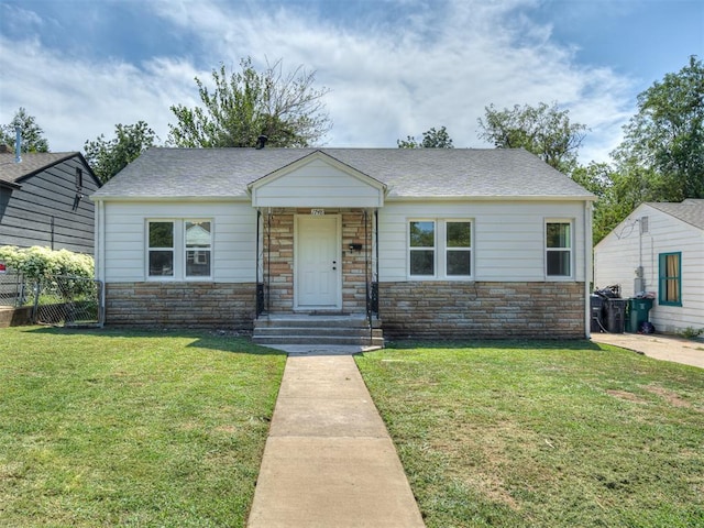 view of front facade featuring stone siding, roof with shingles, fence, and a front lawn